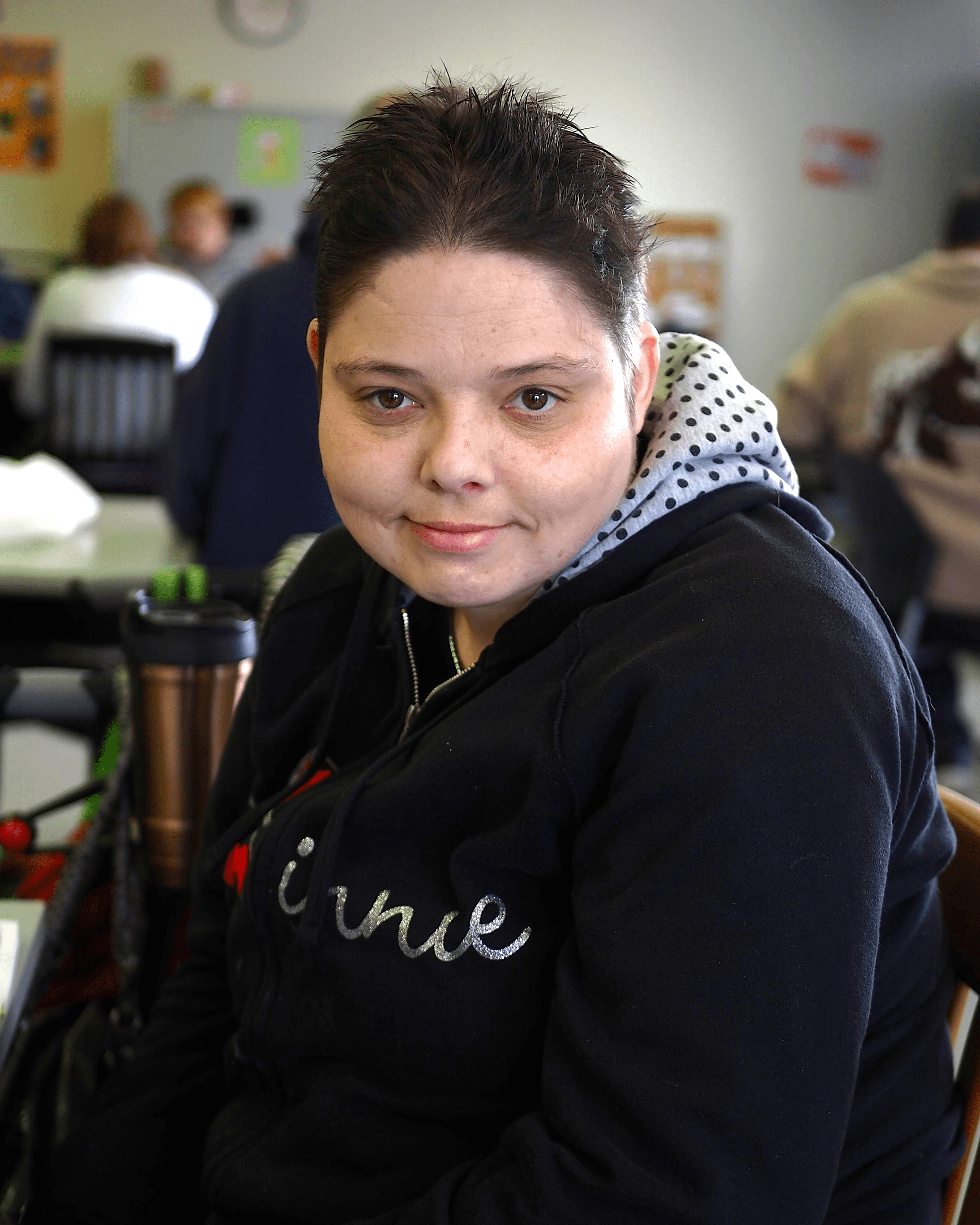 A woman wearing a black sweatshirt is smiling at the camera.