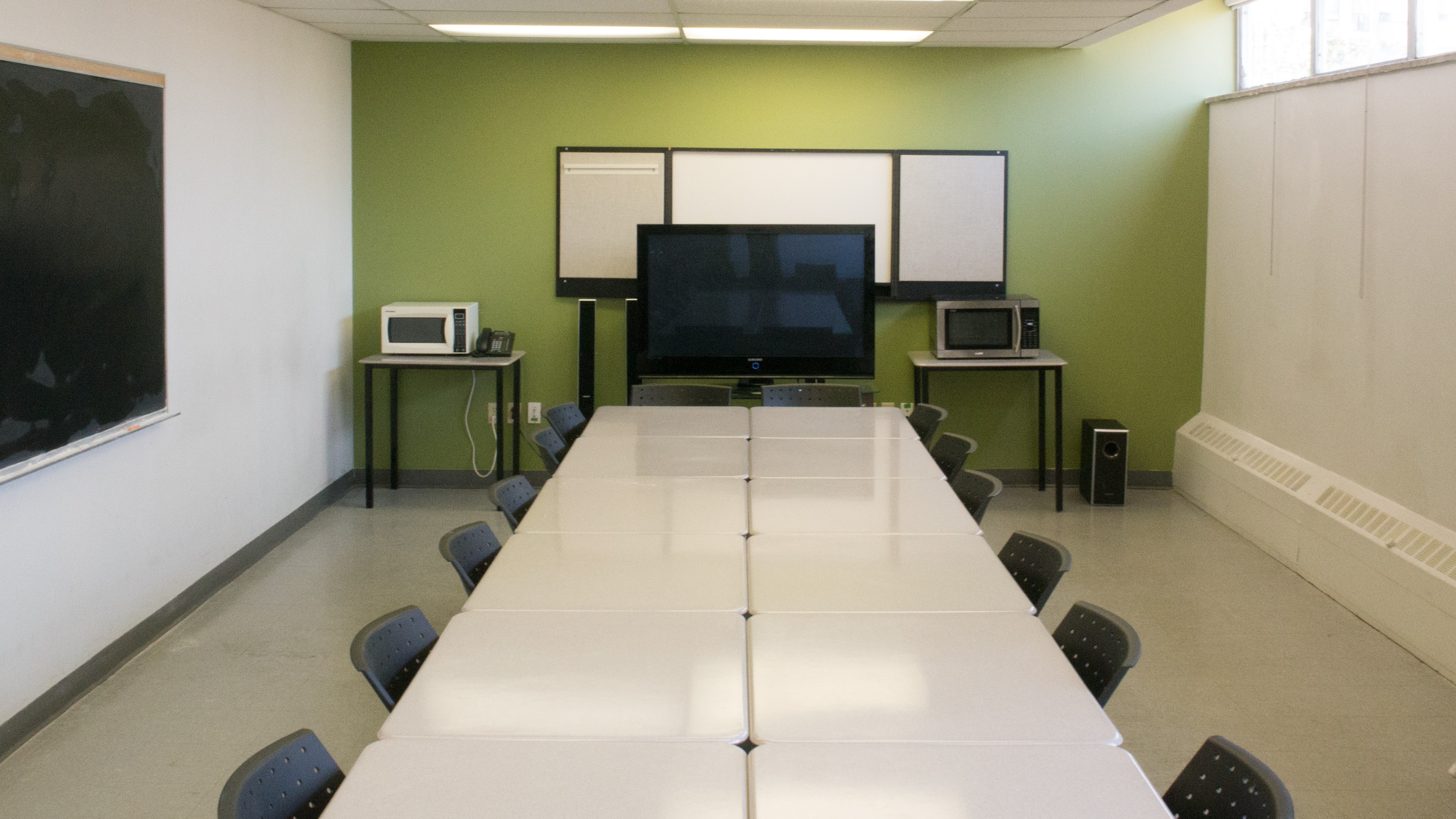 Classroom with tables, blackboard, and TV