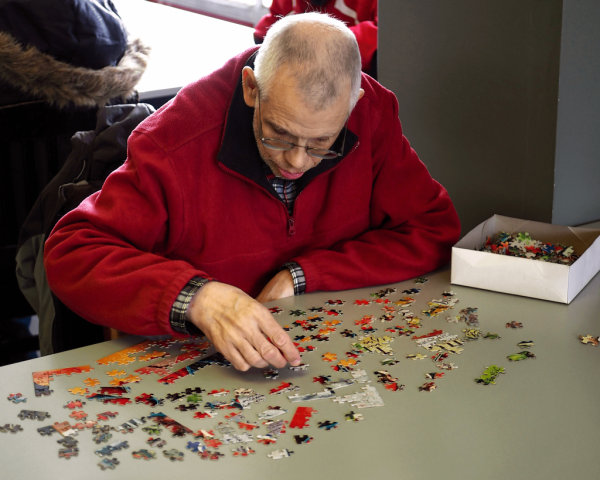 An older man is working on a puzzle.