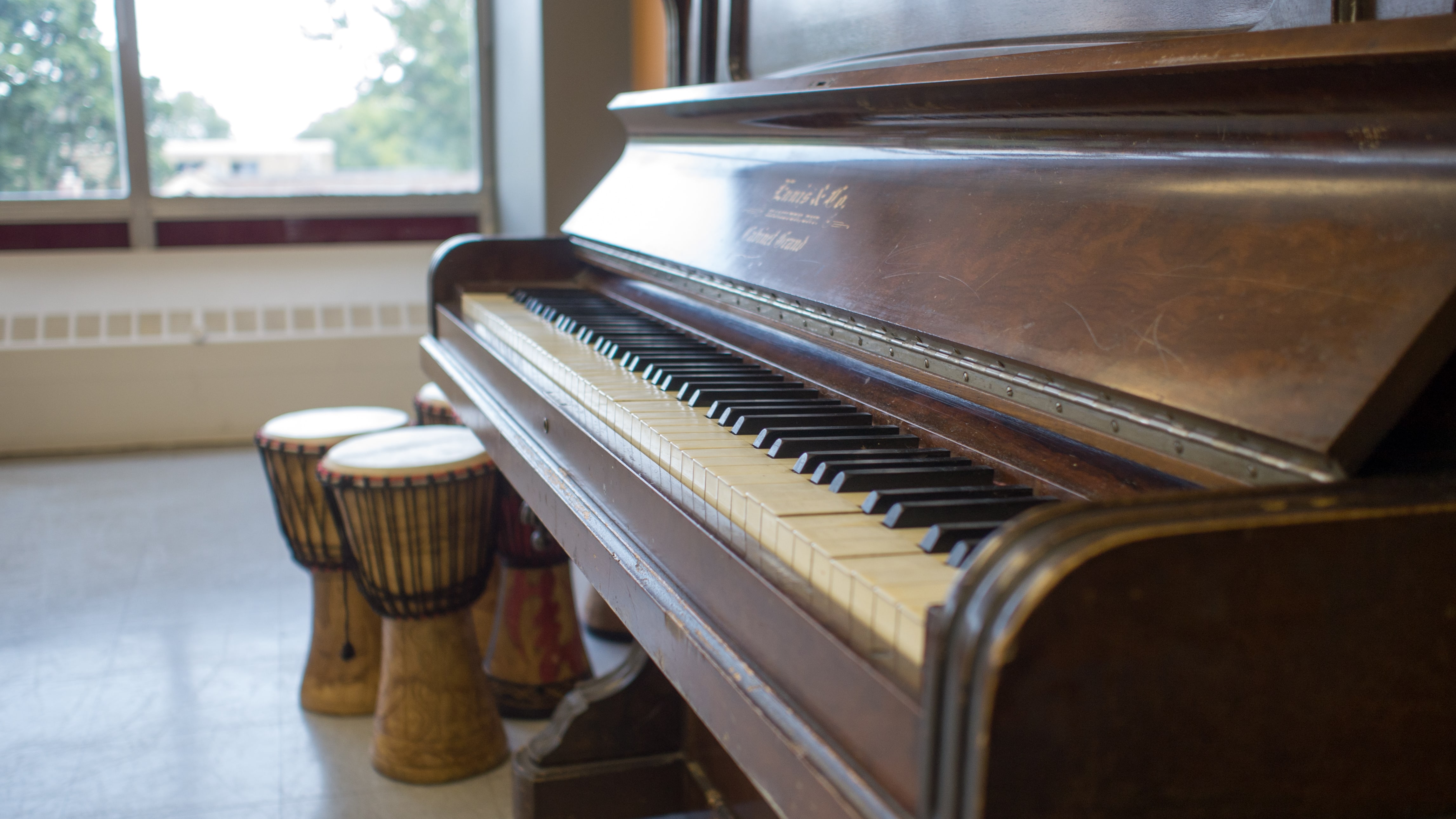 An upright piano and bongos in the Music Room